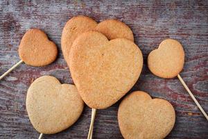 Galletas de jengibre en un palo en forma de corazones se apilan en un montón sobre una mesa de madera foto