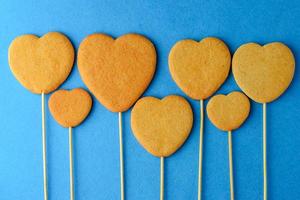 Galletas de jengibre en un palo en forma de corazones sobre un fondo azul. foto