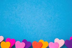 frame of colored wooden hearts at the bottom on a blue background with space for text