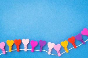 A frame of colored wooden hearts hanging on a rope on a blue background. photo