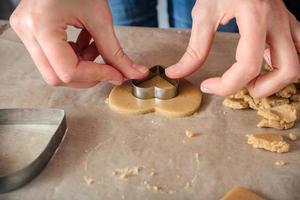 woman making homemade ginger cookies in the form of hearts on a wooden table. photo