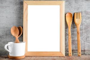 Bastidor de madera vacía y utensilios de cocina sobre una mesa de madera foto