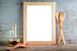 Bastidor de madera vacía con fondo blanco aislado y utensilios de cocina sobre un fondo de madera foto