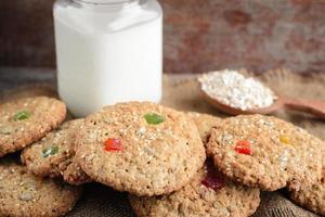 Oatmeal cookies and a glass mug with rustic milk on a wooden table photo