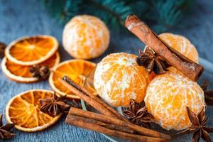Mandarins, dried oranges, anise and cinnamon sticks on a wooden table next to the fir branch