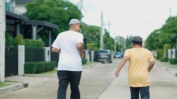 uomo asiatico di mezza età musulmano e suo figlio che si divertono a fare jogging nel suo villaggio la sera video