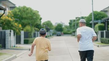 muslimischer asiatischer mann mittleren alters und sein sohn haben spaß beim joggen in seinem dorf am abend video