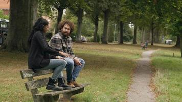 Woman and man talking whilst sitting on bench in park