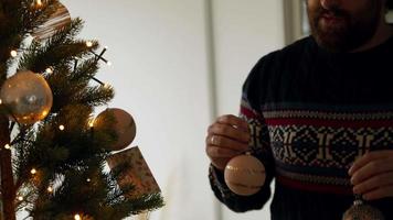 Mann schmückt Weihnachtsbaum mit Kugeln video