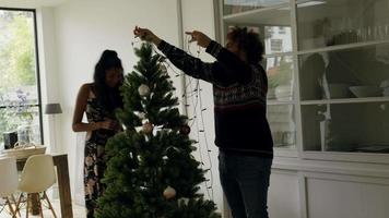 man versiert kerstboom met lichtjes met expliciete instructies van vrouw