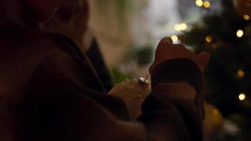Chica sujetando el gancho en la chuchería delante del árbol de navidad video