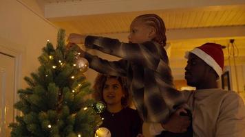 Boy lifted by man decorating tree with bauble and giving high five to woman video