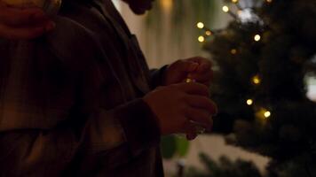 Boy decorating Christmas tree with bauble whilst woman helps and man swings arms video