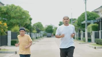 Hombre asiático musulmán de mediana edad y su hijo se divierten haciendo jogging en su pueblo por la noche