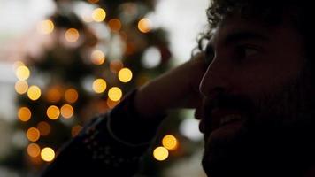 close-up de um homem falando com luzes de natal no fundo