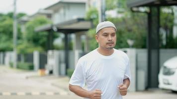 Muslim middle-aged Asian man having fun jogging in his village in the evening video
