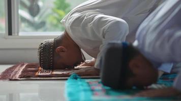 Asian Muslim father and son praying in the evening at his home video