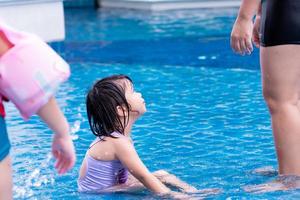 A cute girl sitting in a blue pool looking up. photo