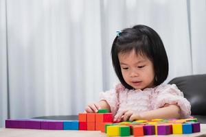 Young girl creative playing colorful toy blocks for homeschooling. Play, learning and imagination concept. photo