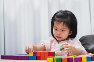Portrait of a child spending her free time doing activity in house. Kid have fun playing with wooden cube toys. photo