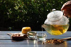 senior people pouring Chrysanthemum tea in from kettle into cup with scone for afternoon tea party in gardeng photo