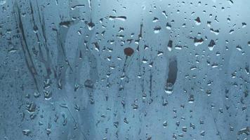 des gouttes d'eau coulent sur le verre embué avec un arrière-plan flou video