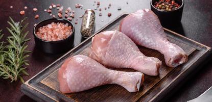 Fresh raw chicken legs with spices, salt and herbs on a cutting board photo