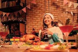 Sonrisa de felicidad joven mujer caucásica en un restaurante con alimentos especiales como pavo asado y vino en la fiesta de celebración de Navidad en el comedor decorado para el festival alegre y feliz año nuevo.