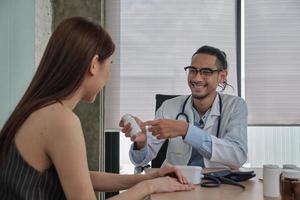 tratamiento médico y chequeo, un joven médico habla con una sonrisa y examina a una paciente de etnia asiática durante una visita de consulta de salud, asesorar en una clínica de hospital.