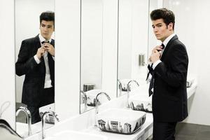 Man getting dressed in a public restroom with mirror photo