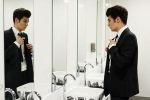 Man getting dressed in a public restroom with mirror photo