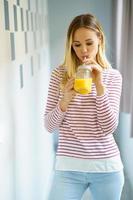 Caucasian woman drinking a glass of natural orange juice at home.