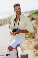 hombre sonriente fotografiando en una zona costera. foto