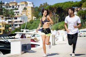 Pareja joven entrenando juntos corriendo cerca de los barcos en un puerto foto