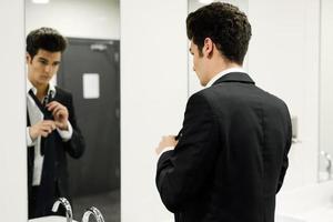 Man getting dressed in a public restroom with mirror photo