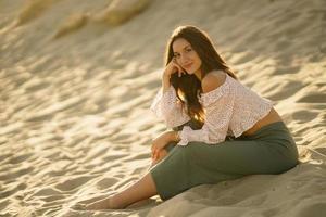 atractiva mujer sentada en la arena de la playa foto