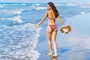 Woman in swimwear and sunhat, enjoying the beach on her holiday. photo