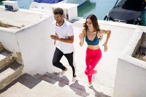 Athletic couple training hard by running up stairs together outdoors. photo