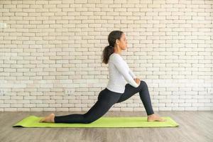 Latin woman practicing yoga on mat photo