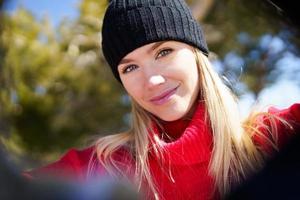 Young blonde woman taking a selfie in a snowy mountain forest in winter. photo