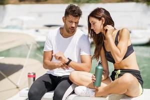 Man showing his marks to a woman on a sports watch after exercise. People using smartwatch.