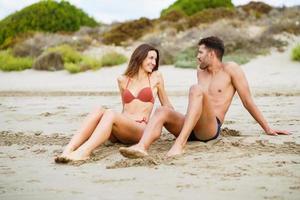 Young couple sitting together on the sand of the beach