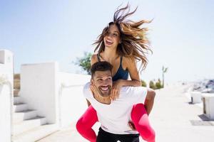 Man carrying his girlfriend on piggyback wearing sport clothes. photo
