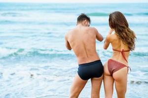 Young couple with beautiful bodies in swimwear having fun on a tropical beach