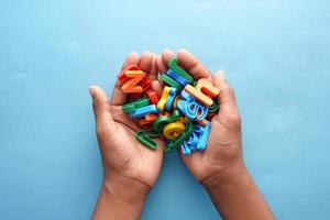 Letras de plástico de colores en la mano del niño sobre fondo azul. foto