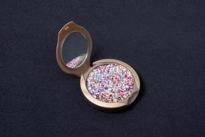 Makeup powder and cosmetic brush with glitter stars on black background