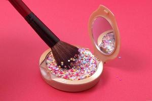 Makeup powder and cosmetic brush with glitter stars on red background photo