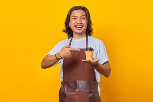 Portrait of positive cheerful man holding paper cup with finger showing sales discount over yellow background photo