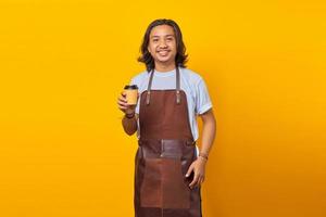 Portrait of cheerful positive handsome man  holding paper cup over yellow background photo