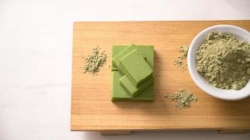 Barre de chocolat au thé vert matcha frais et doux sur planche de bois avec poudre de thé vert - style dessert japonais